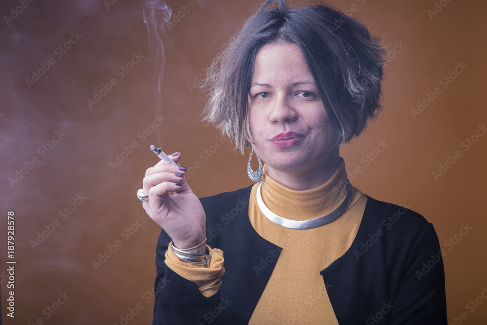 Fototapeta premium Portrait of a young woman smoking a cigarette on a yellow background