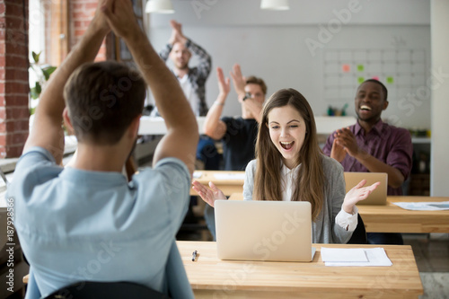 Excited woman looking at laptop screen surprised by good online news win achievement, corporate team colleagues congratulating coworker with business success clapping hands in coworking shared office © fizkes