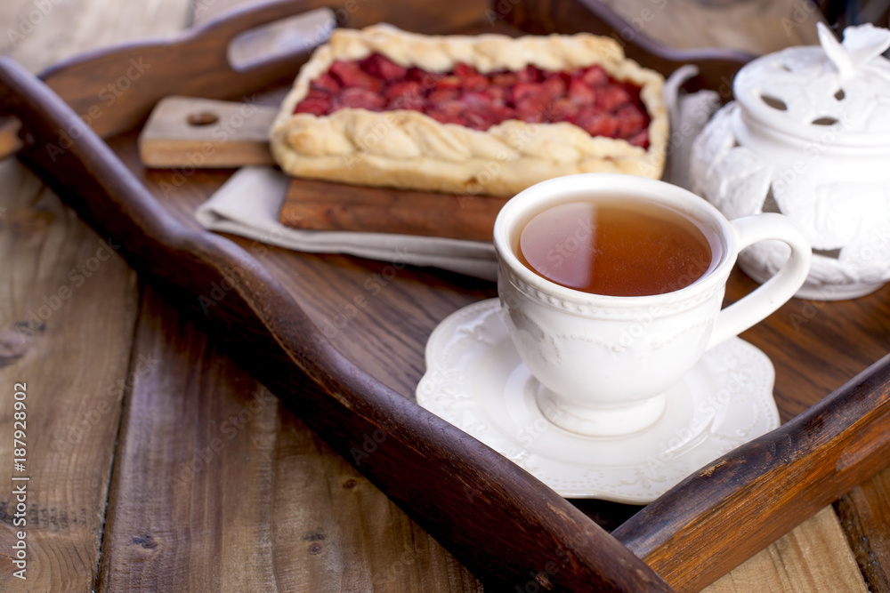 Sweet home-made pie for breakfast and a cup of black tea, on a krchovom wooden tray. free space for text or advertising Sweet home-made pie for breakfast and a cup of black tea, on a krchovom wooden tray. free space for text or advertising