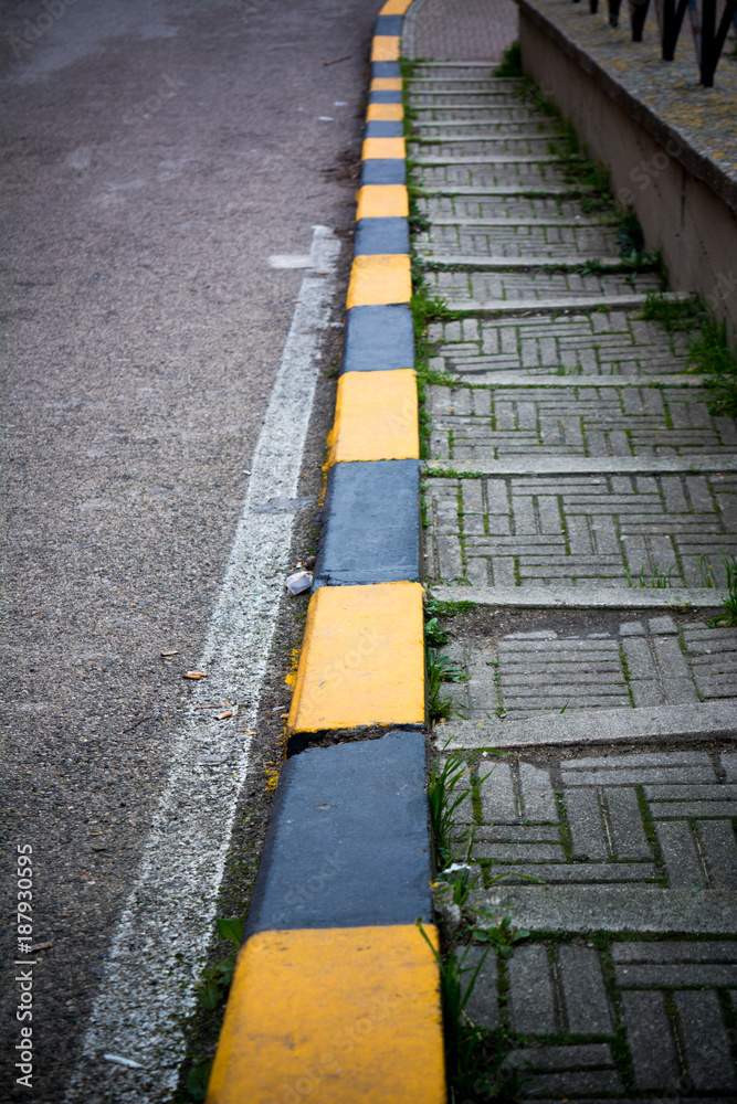 Vertical View Of a Stoned Stair Along The Street With Black and Yellow Markings.