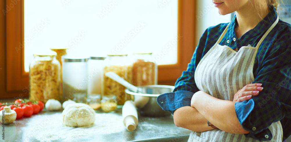 Fototapeta premium Beautiful woman cooking cake in kitchen standing near desk