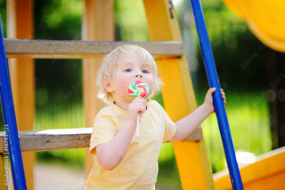 Little boy having fun and eating big lollipop on outdoor playground Little boy having fun and eating big lollipop on outdoor playground