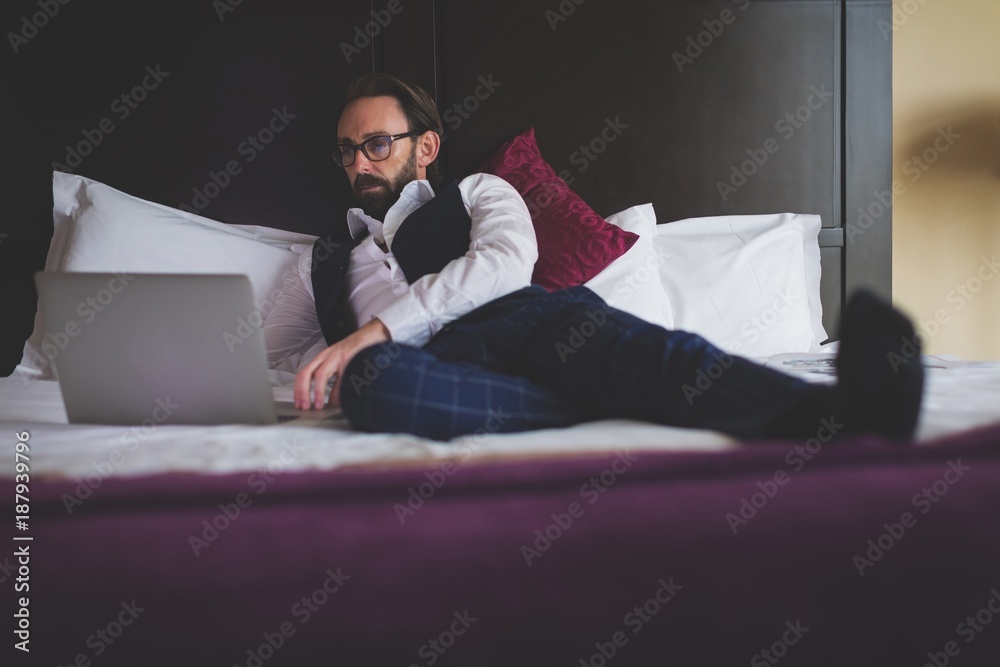 Businessman using laptop on bed Businessman using laptop on bed