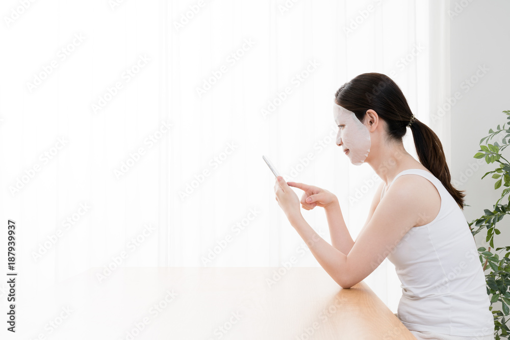フェイスマスクをする女性、スマートフォン フェイスマスクをする女性、スマートフォン