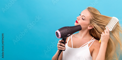 Beautiful woman holding a hairdryer on a blue background