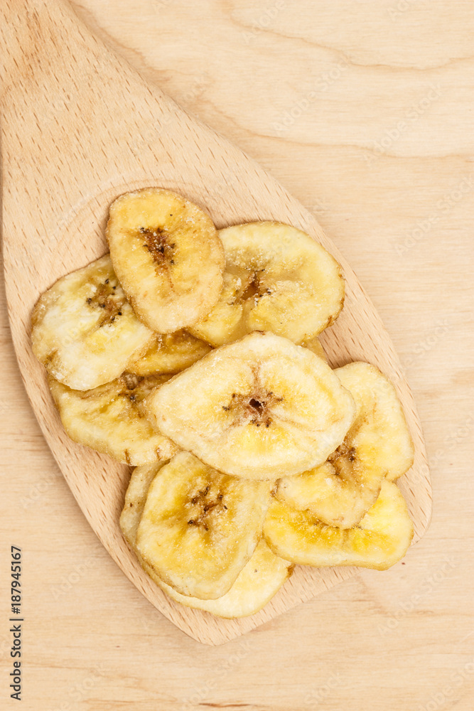 Heap of dried banana chips on wooden spoon Heap of dried banana chips on wooden spoon
