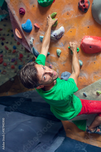 A rock climber is in a bouldering hall.