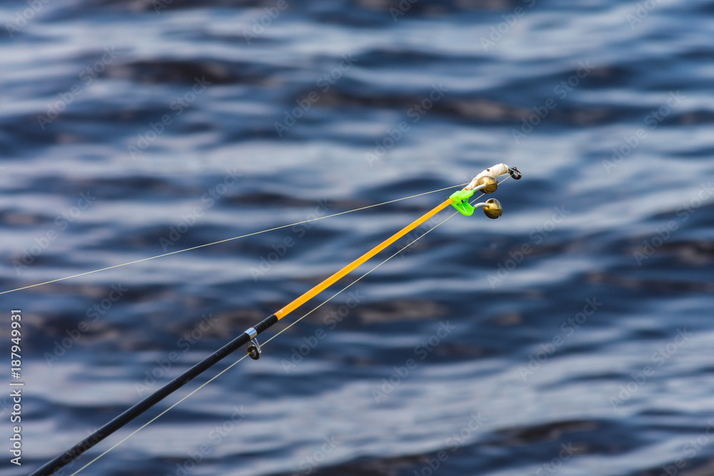 A beautiful rod with a bell on a background of lake A beautiful rod with a bell on a background of lake