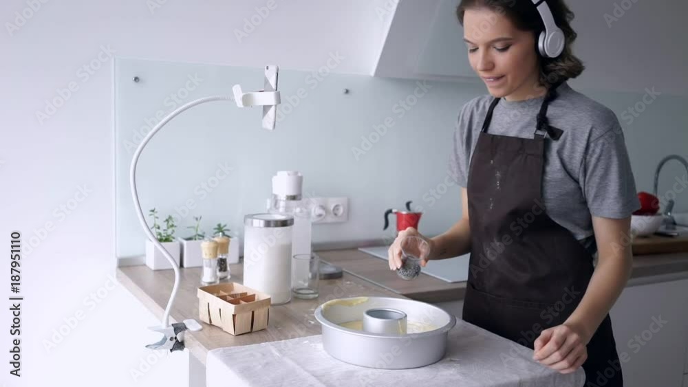 Happy brunette woman in headphones prepares a pie on kitchen Happy brunette woman in headphones prepares a pie on kitchen