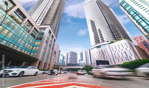 Blured car traffic on skyscrappers and blue sky background. Life in busy megapolis.  photo