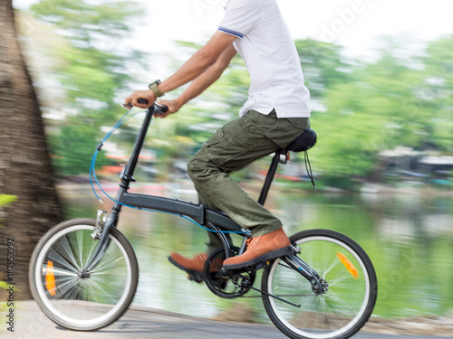 panning camera technique in slow speed shutter. Man with cargo pants riding a bicycle in the garden