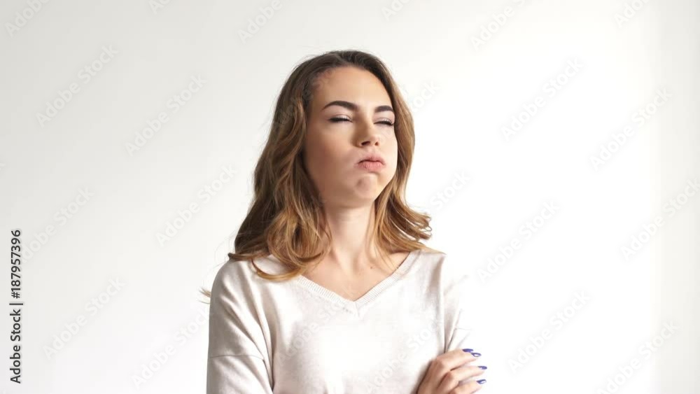 Angry brunette woman quarrells and looking around over grey background Angry brunette woman quarrells and looking around over grey background