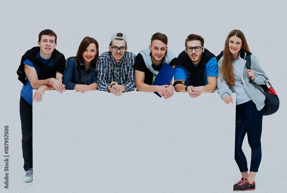 Full length portrait of confident college students displaying blank billboard against white background.