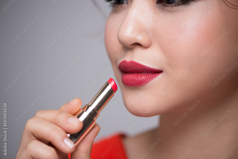 Closeup portrait of beautiful girl putting on red lipstick Closeup portrait of beautiful girl putting on red lipstick