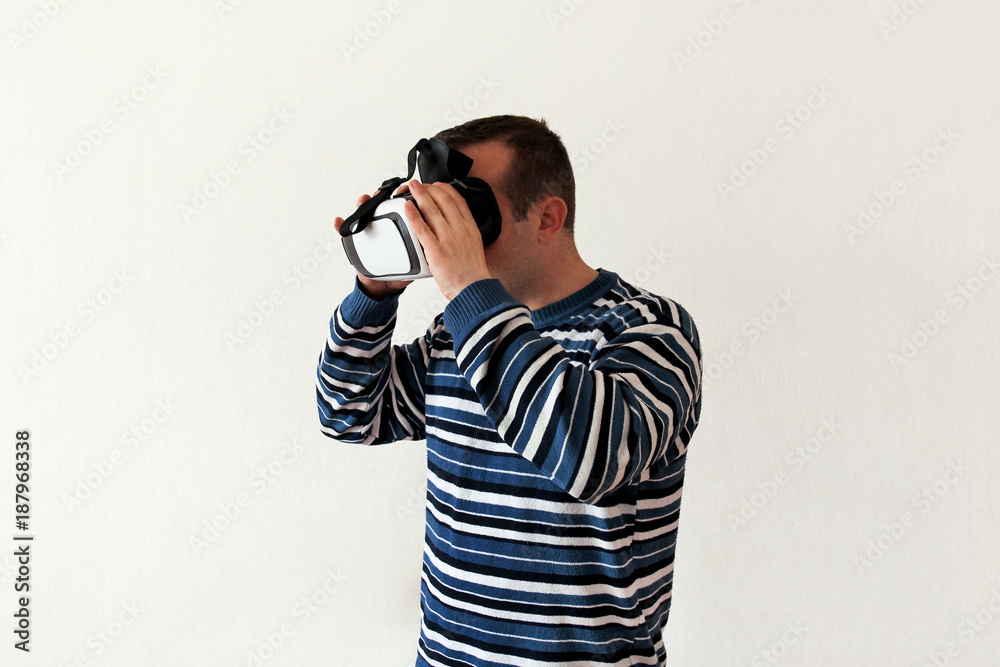 Man wearing and playing mobile game app on device virtual reality glasses on white background. Man action and using in virtual headset, VR box for use with smart phone. Contemporary technology concept Man wearing and playing mobile game app on device virtual reality glasses on white background. Man action and using in virtual headset, VR box for use with smart phone. Contemporary technology concept