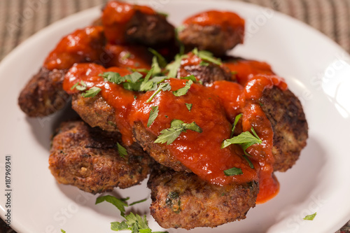 Close up of fried meatballs made from pork and beef meat with tomato sauce and herbs