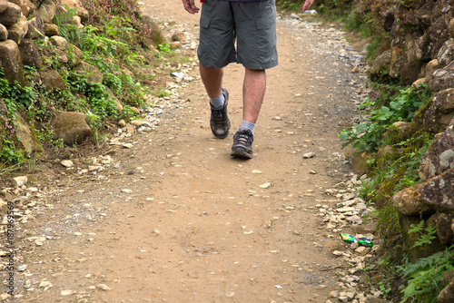 Close up male legs walking on nature road of up country village, walking along trail, trekking or hiking 