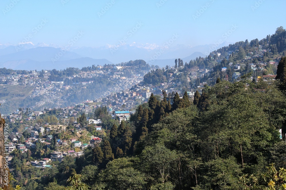 Fototapeta premium Random houses on a mountain valley with snow clad mountains in background