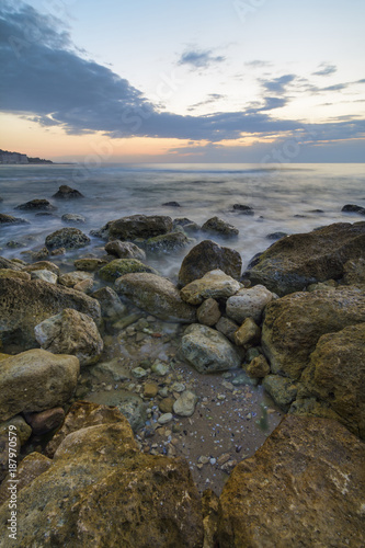 seascape of Silky sea with rocks against a colorful sky at sunrise .