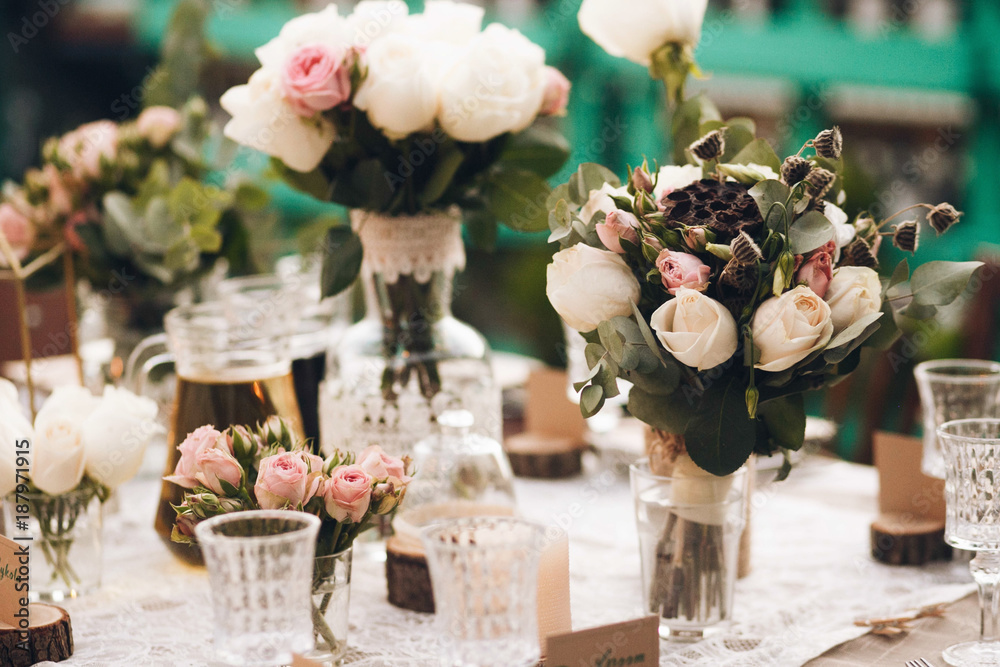 Little dinner table served in rustic style and decorated with pink flowers stands outside