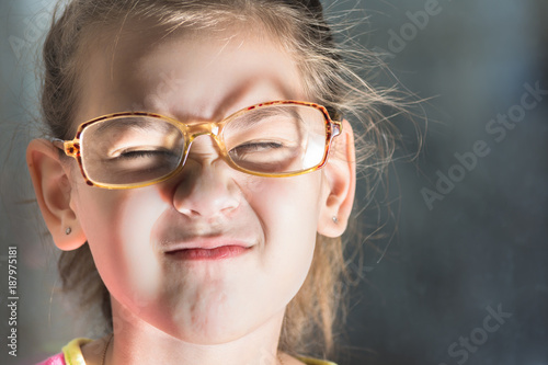 Beautiful child with glasses squinting from the light