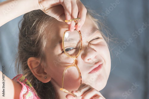 Beautiful child is trying on glasses to face