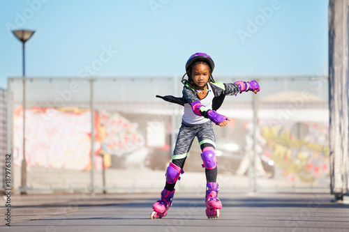 African girl rollerblading fast at skate park photo
