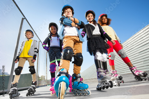 Boy in rollerblades standing with friends outdoors