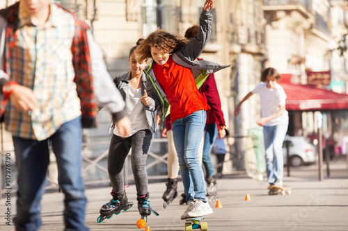 Happy teen skateboarding with friends at side walk