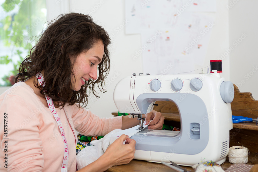Young seamstress woman using sewing machine to design clothes - Do it youself theme - obrazy, fototapety, plakaty 