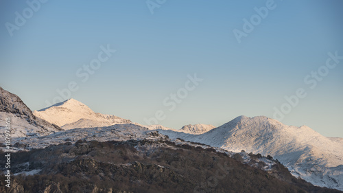 Beautiful Winter sunrise landscape image of Mount Snowdon and other peaks in Snowdonia National Park