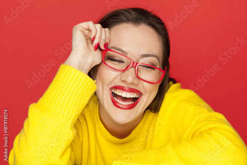 beautiful happy woman with red glasses on red background