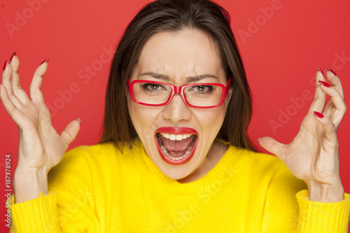 beautiful angry woman with red glasses on red background