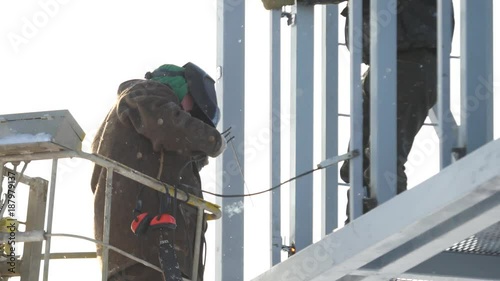 Construction workers working on scaffolding, Man Working on the Working at height with blue sky at construction site. Worker using electric wheel grinding on steel structure in factory. Work on high photo