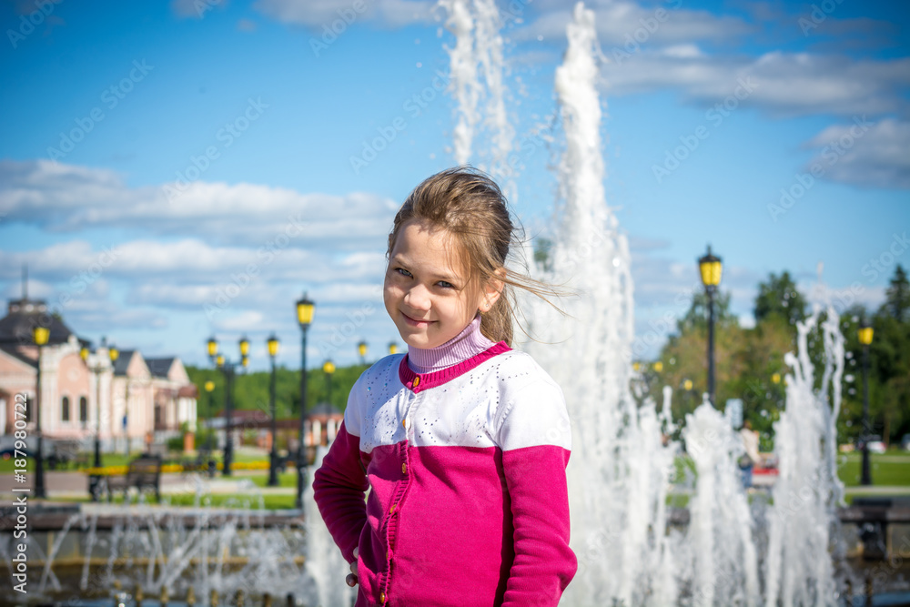 Naklejka premium Happy child posing at the fountain in the Park