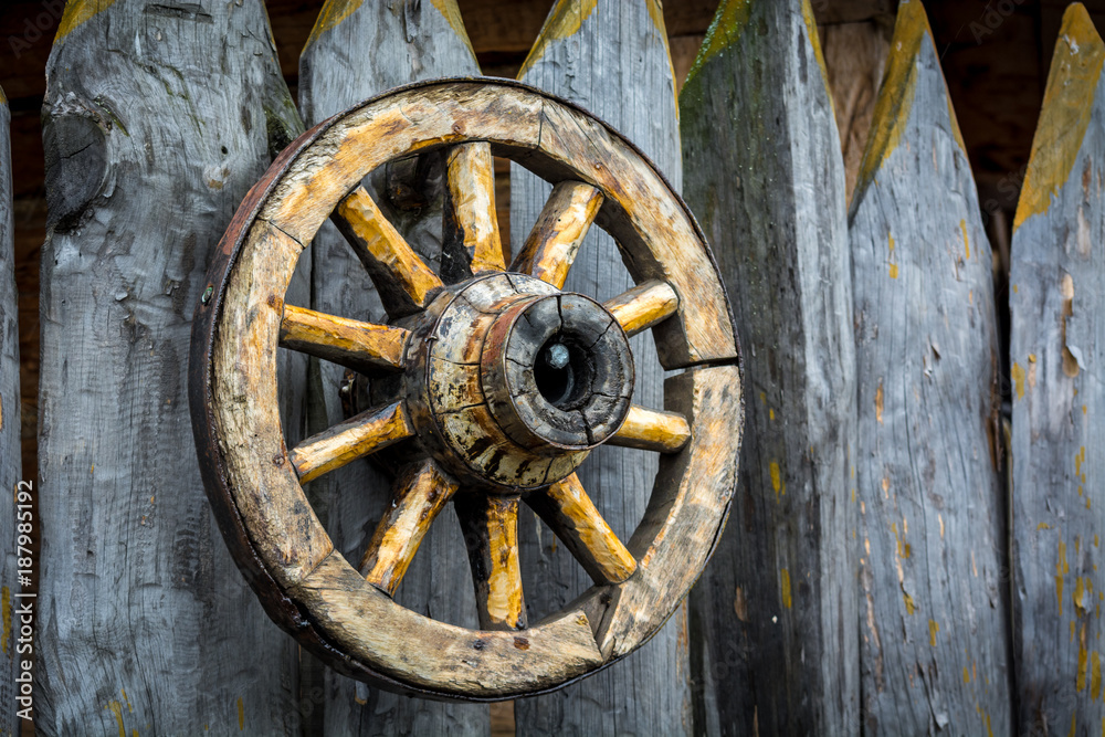 Old wooden cart wheel hanging on the fence
