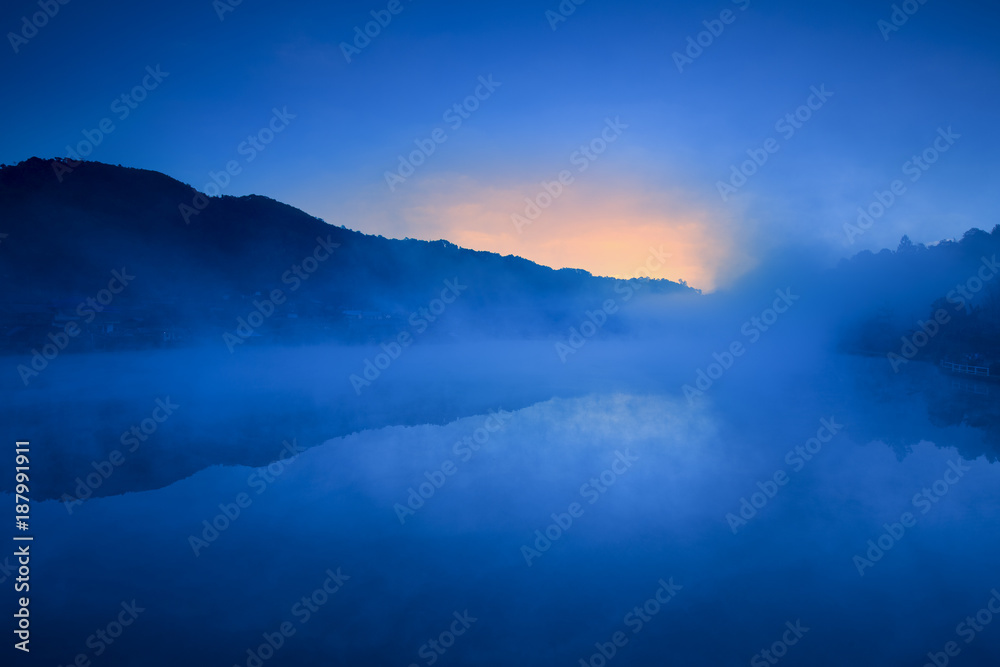Naklejka premium Mysterious misty morning over village in mountain and lake.