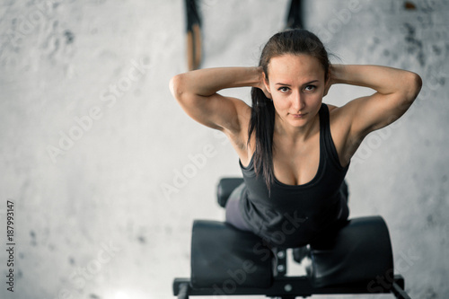 Young sporty woman workout on exercises for buttocks on bench photo