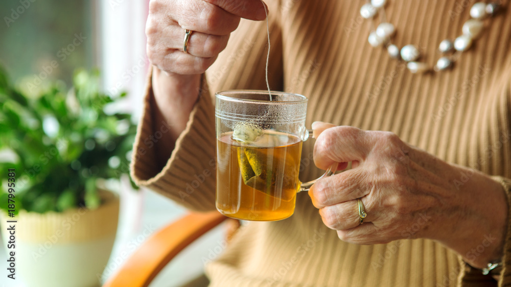 older woman hand holding a glass of tea. older woman hand holding a glass of tea.