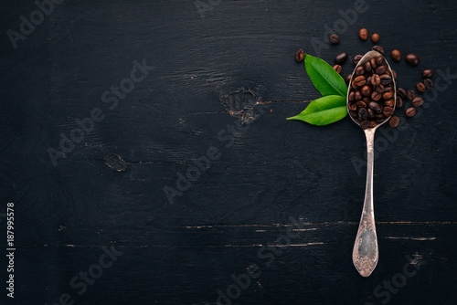 Coffee beans. On a spoon lie on a wooden background. Top view. Copy space.