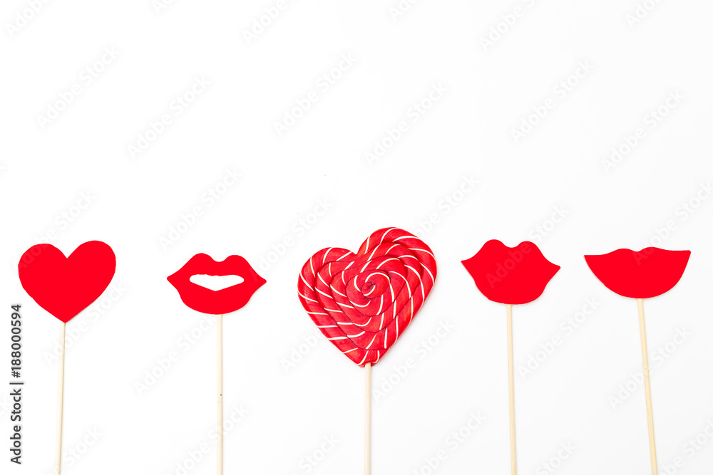 Red lips and lollipop in the shape of a red heart on a white background. Copy space