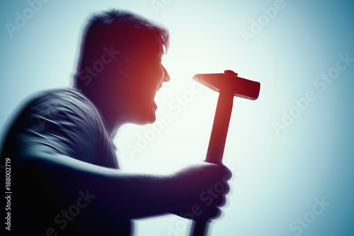An aggressive man attacks with a hammer. Assault with a hammer. Hand with a hammer. Murder with a hammer.