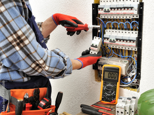 Young electrician technician at work on a electrical panel with protective gloves