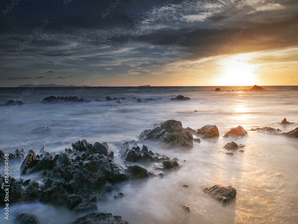 Naklejka premium Rocks in the ocean at sunset time
