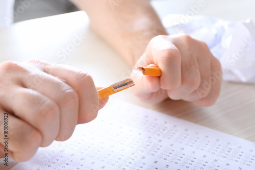 Stressed student breaking pencil while taking exam at table