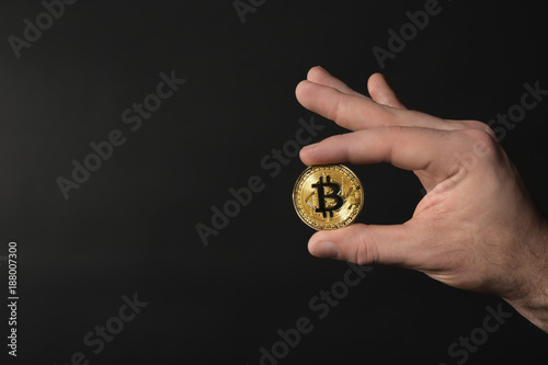 Male hand with golden bitcoin on dark background