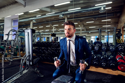 Businessman doing exercises with dumbbells in the gym.