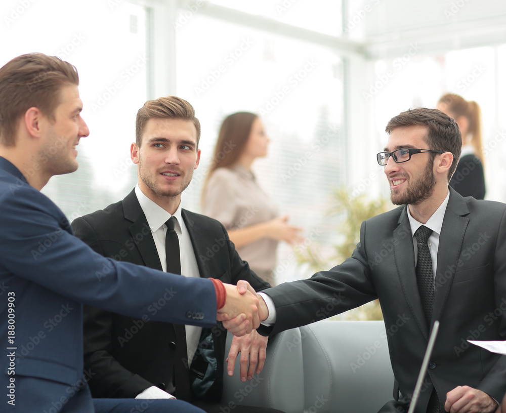 Partners concluding deal and shaking hands in the presence of team members Partners concluding deal and shaking hands in the presence of team members