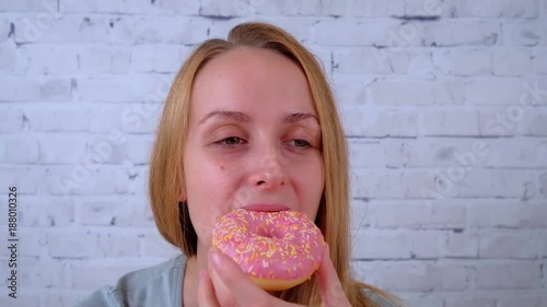 Smiling young woman eating a donut and drinking coffee photo