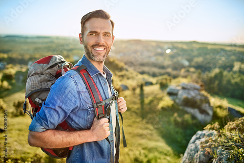 Portrait of cheerful man with backpack during hiking trip in the mountains
